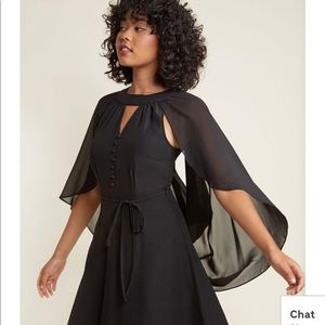 “Icing on the Cape A-Line Dress” in Black